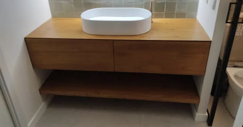 Reforma de baño moderno con mueble de madera y lavabo oval