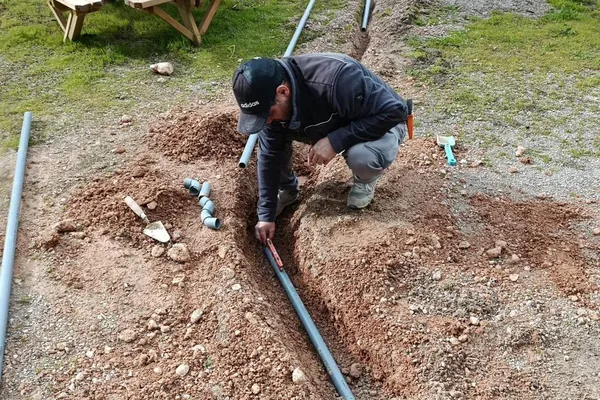 Fontanero de HRVS instalando canalización de agua en excavación exterior