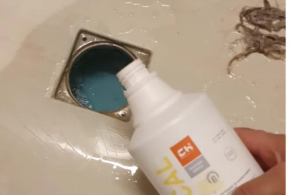 Fontanero aplicando tratamiento descalcificador en desagüe de baño
